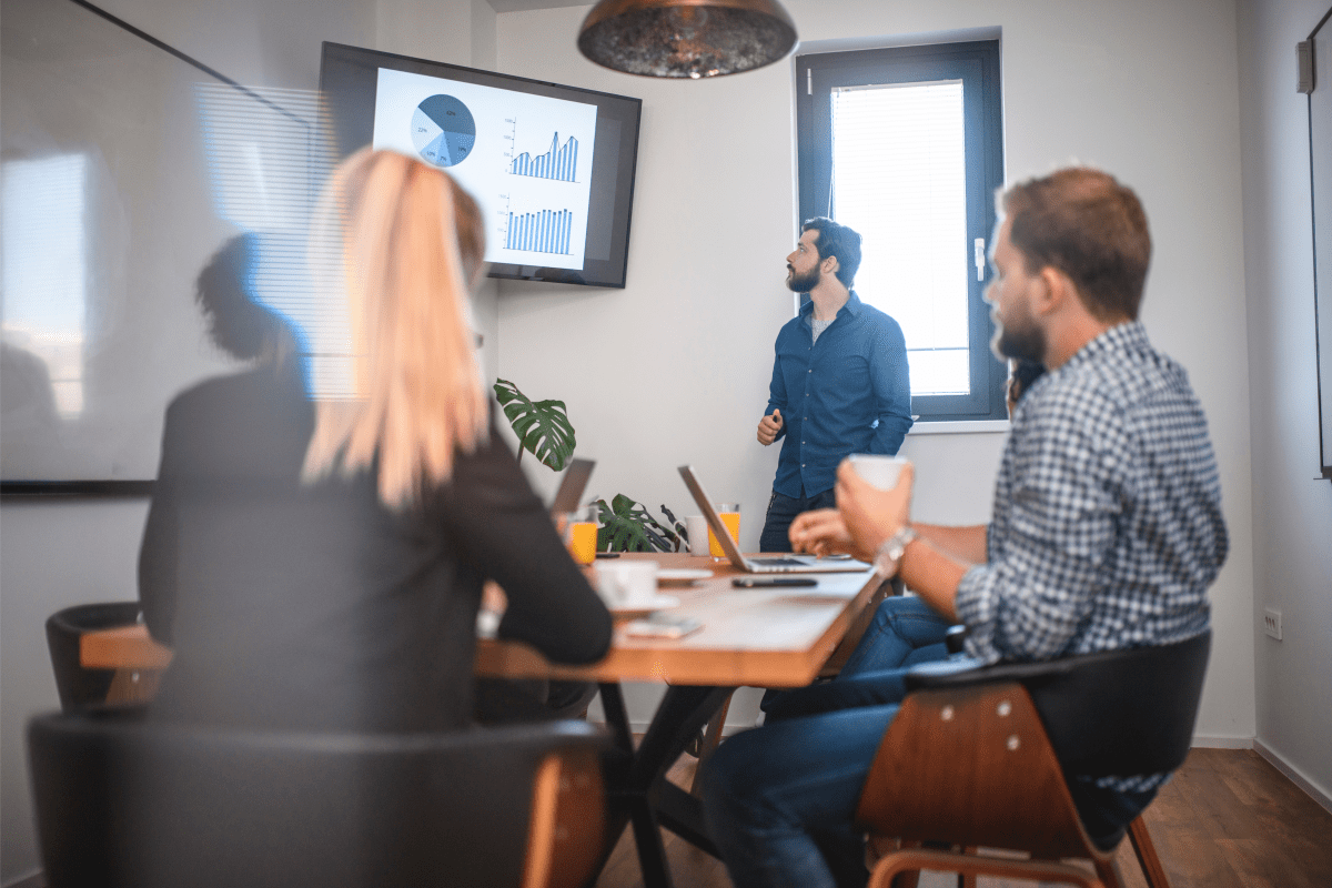 Young Caucasian businessman presenting slide show to male and female colleagues in office conference room.